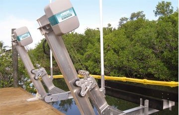 Silver and teal IMM Quality elevator boat lift is an Alumavator model mounted to a brown dock