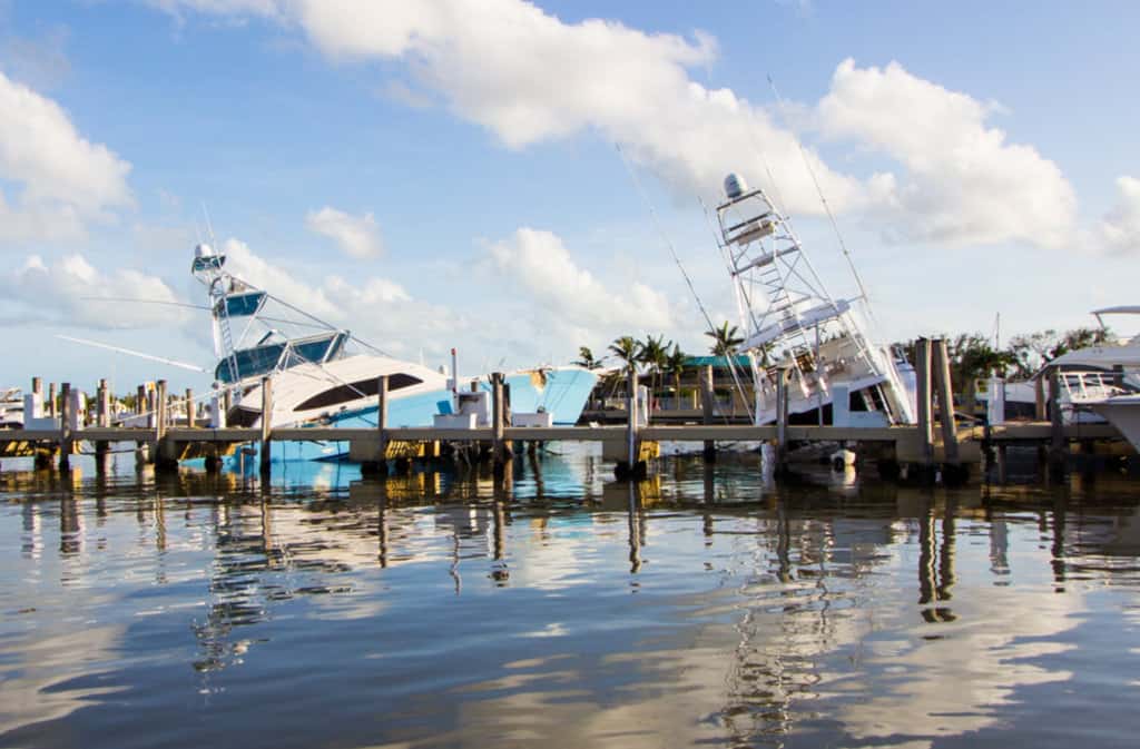 Two leaning boats in marina show the hidden cost of boat ownership after a storm