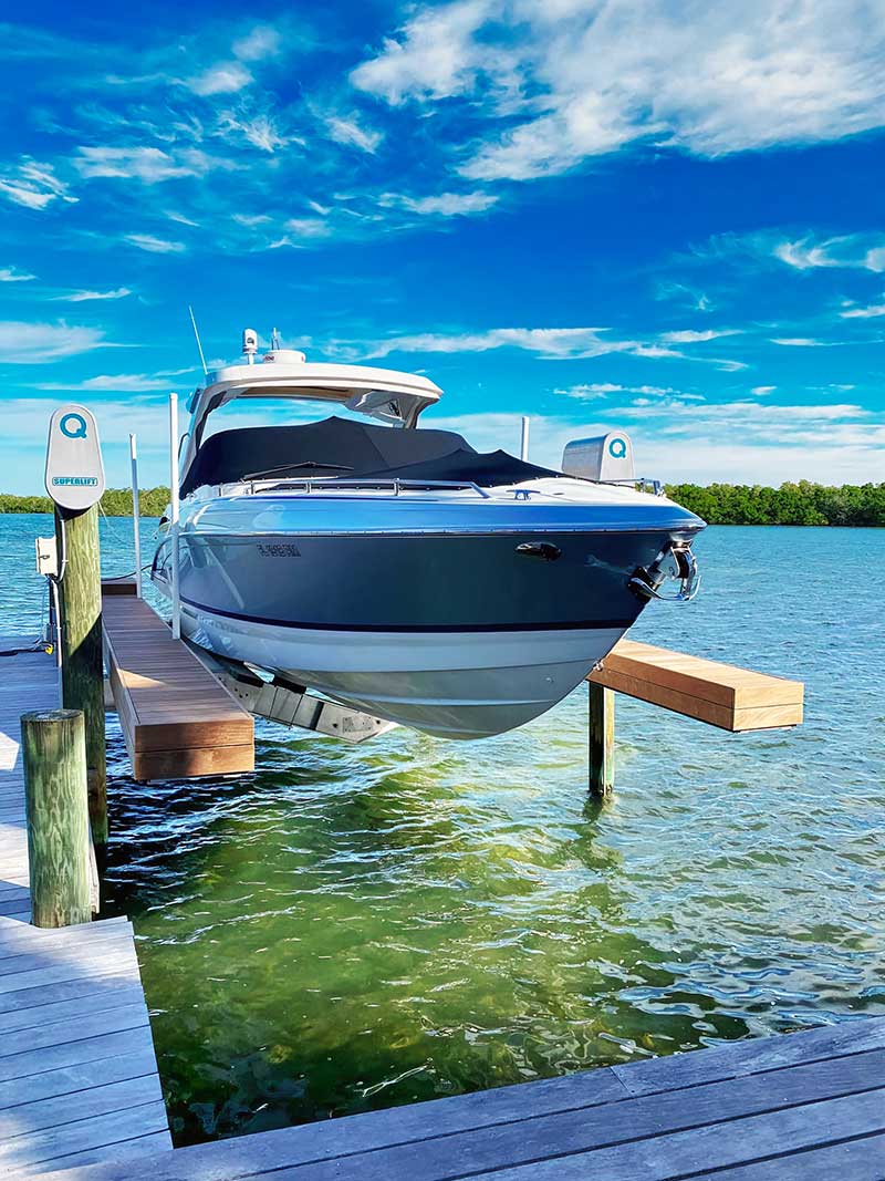 Large navy and white boat sits on Thaler 2 Superlift vertical boat lift helps this boat avoid salt water damage and fresh water damage