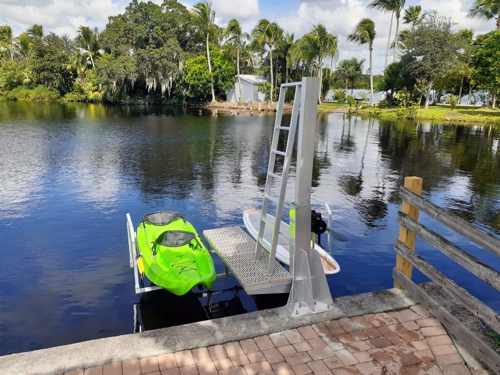 bright green kayak and white paddleboard are secured on this IMM Quality dual kayak lift