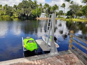 bright green kayak and white paddleboard are secured on this IMM Quality dual kayak lift