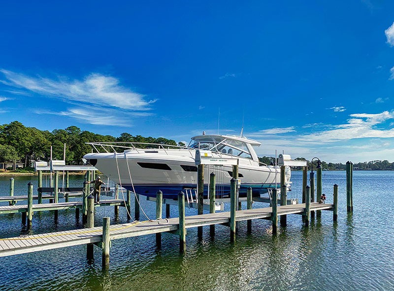 This photo shows what is a boat lift as white boat is raised from the water by an IMM Quality boat lift